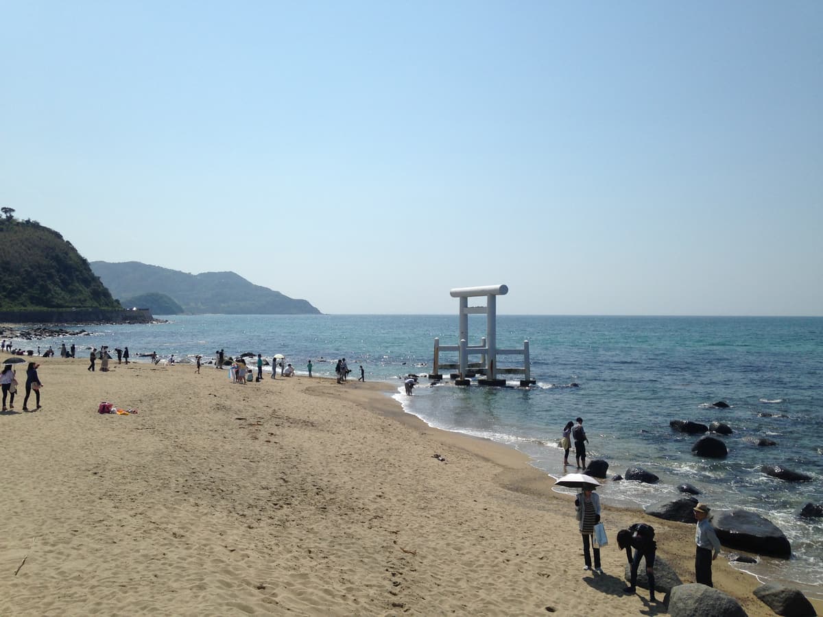 The white torii gate standing on the sand at Futamigaura beach, Itoshima